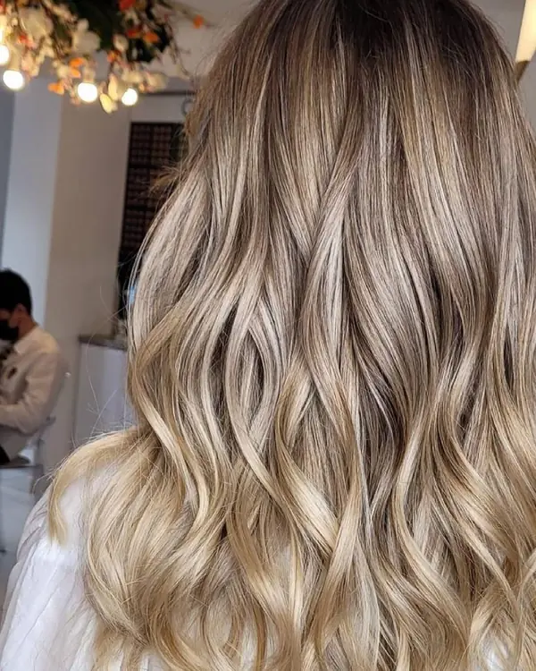 Long wavy hair seen from behind, dark roots melting into soft blonde ends.