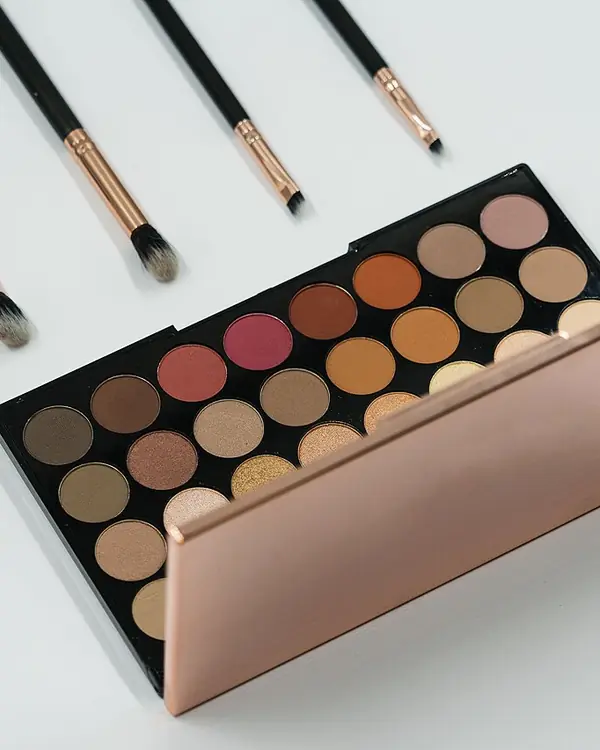 An eyeshadow palette in warm browns, with fine makeup brushes.