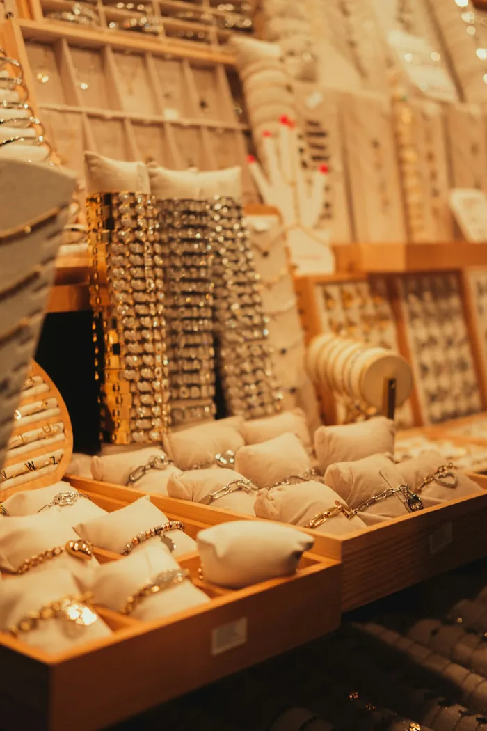 Gold bracelets and chains resting on cream cushions in a warmly lit display case.