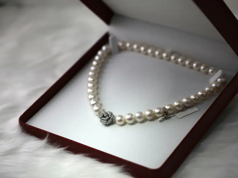 A pearl necklace lying in an open red box.