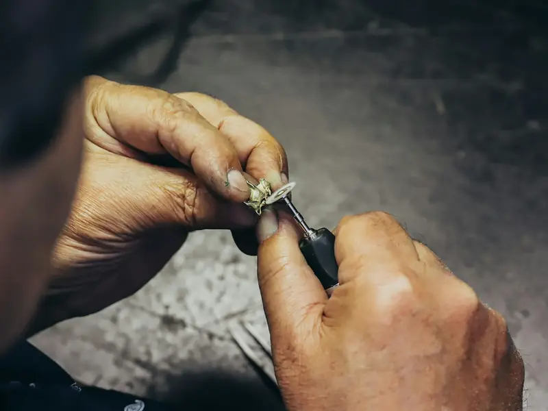 A jeweller's hands shaping a ring with a fine tool.