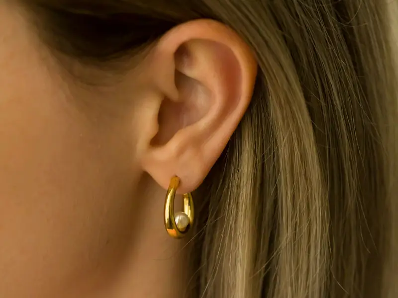 A small gold hoop in an earlobe, seen close up.