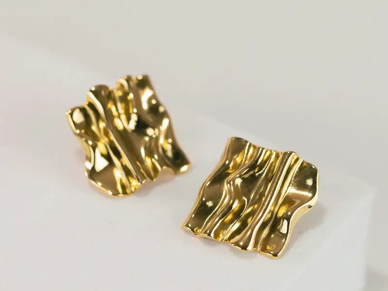 Two textured gold studs on a white block.