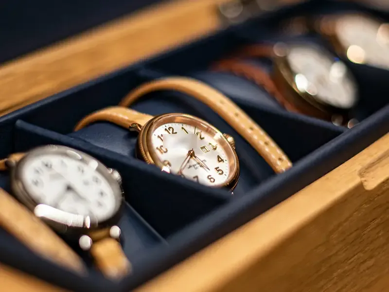 Tan-strapped watches lying in the compartments of a wooden box.